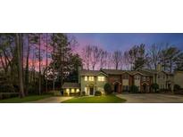 Charming townhome with beautiful landscaping and mature trees against a colorful sunset sky at 250 Peachtree Hollow Ct, Atlanta, GA 30328