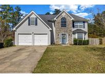 Charming two-story home featuring a two-car garage, stone accents, and manicured front lawn at 6031 Autumn Green Dr, Fairburn, GA 30213