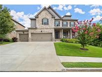 Charming two-story brick home featuring a manicured lawn, three-car garage, and inviting front porch at 4316 Woodland Bank Blvd, Buford, GA 30518