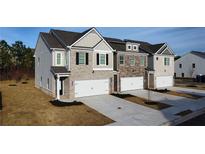 Modern townhomes boast brick and siding exteriors with attached garages and newly landscaped lawns at 167 Belldown Ct, Mcdonough, GA 30253