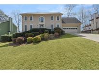 Charming two-story home featuring a well-manicured lawn, a two-car garage, and mature landscaping at 820 Hounds Ridge Ct, Lawrenceville, GA 30043