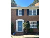 Charming brick townhouse featuring a blue front door, black shutters, and manicured landscaping at 4620 Wieuca Ne Rd # 32, Atlanta, GA 30342