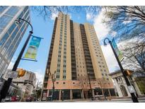 Exterior view of high-rise apartment building with beige facade and large windows in a lively city setting at 300 W Peachtree St # 21K, Atlanta, GA 30305