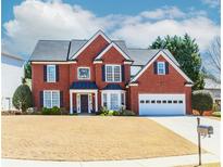 Beautiful two-story brick home with a manicured front lawn and attached two car garage at 1825 Embassy Walk Ln, Lilburn, GA 30047