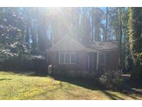 Cozy single-story home featuring a well-maintained lawn and mature trees, with light shining through the trees at 1833 Ridgeland Dr, Decatur, GA 30032