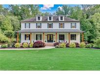 Charming two-story home featuring a inviting front porch with swing seating and lush landscaping at 650 Jones Rd, Roswell, GA 30075