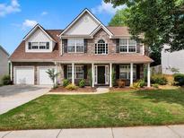 Charming two-story home with stone accents, a well-manicured lawn, and a welcoming front porch with white columns at 3725 Crescent Walk Ln, Suwanee, GA 30024