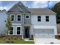 Charming two-story home featuring a mix of gray and white siding, a two-car garage, and a well-manicured front yard at 4300 Easter Lily Ave Lot 11, Buford, GA 30519