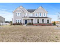 Charming two-story home featuring a symmetrical facade, light gray siding, and a well-manicured lawn at 105 Marchmont Dr, Locust Grove, GA 30248