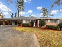 Charming single-story brick home featuring a covered parking area and a well-manicured front yard at 2159 Pinehurst Rd, Snellville, GA 30078