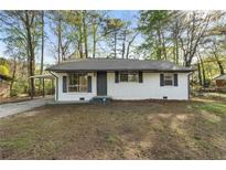 Charming white brick home featuring a cozy front yard and black shutters at 7323 Howard Pl, Jonesboro, GA 30236
