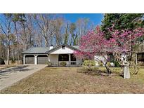 Charming home featuring a two-car garage and a beautifully landscaped front yard with a blooming tree at 209 Park Ave, Woodstock, GA 30188