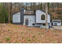 Two-story home featuring vertical siding, an arched window, and a small shed on a wooded lot at 1291 Marcelle Heights Pl, Norcross, GA 30093