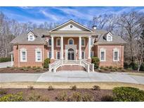Stately brick home featuring symmetrical design, manicured landscaping, and a grand entrance staircase at 350 Newcastle Dr, Alpharetta, GA 30009