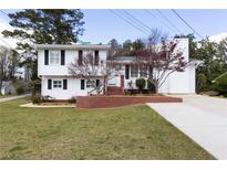 Charming split-level home featuring a manicured lawn, brick accents and a long driveway at 1316 Milstead Ave, Conyers, GA 30012