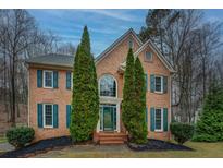 Charming two-story brick home featuring teal shutters, green front door, and manicured landscaping at 2070 Sweetgum Trl, Cumming, GA 30041