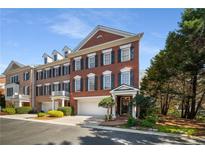 Brick townhome featuring three stories with dormers, attached garage, and manicured landscaping at 2314 English Ivy Se Ct, Atlanta, GA 30339