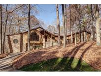 Secluded home with stone and wood exterior, nestled amongst mature trees in a wooded setting at 935 Pine Grove Pointe Dr, Roswell, GA 30075