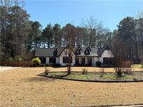 Charming white-painted house featuring a modern black roof, dark shutters, and a spacious front yard with mature trees at 165 Sugarland Trl, Fayetteville, GA 30214