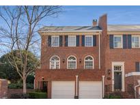 Beautiful brick townhome featuring a two-car garage, black shutters and a well manicured front yard at 208 Jefferson Cir, Atlanta, GA 30328