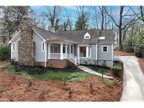 Charming gray cottage-style home featuring a stone chimney, inviting front porch, and beautifully landscaped front yard at 3776 Powers Ferry Nw Rd, Atlanta, GA 30342