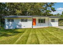 Charming single-story home with manicured lawn, white exterior, and bright orange front door at 1554 Pine Ct, Conley, GA 30288