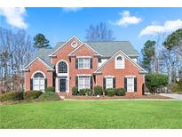 Charming two-story red brick home with lush green lawn and well-maintained landscaping at 325 Stonecastle Pass, South Fulton, GA 30331