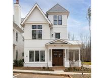 Charming two-story home with a white facade, covered front porch and professionally landscaped yard at 11572 Serenbe Ln, Chattahoochee Hills, GA 30268