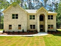 Charming, light brick two-story home featuring a manicured lawn and a welcoming, arched entryway at 123 Honey Creek Rd, Conyers, GA 30094