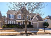 Charming two-story home featuring a stone facade, manicured landscaping, and a two-car garage at 111 Edgewater Trl, Canton, GA 30115