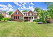 Beautiful brick two-story home with a lush lawn and welcoming front porch at 3070 Corsair Curv, Cumming, GA 30040