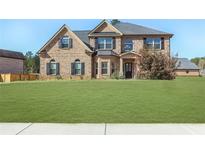 Two-story brick home with a manicured front lawn and symmetrical window and shutter design at 7347 Moss Stone Dr, Conyers, GA 30094