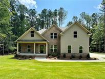 Inviting two-story home featuring a brick facade, covered porch, well-manicured lawn, and lush landscaping at 125 Honey Creek Rd, Conyers, GA 30094