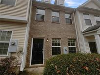 Brick front exterior of a two-story townhome with a black front door and manicured shrubbery at 474 Berckman Nw Dr, Lilburn, GA 30047