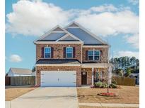 Charming brick two-story home with a well-manicured front yard and attached two-car garage at 3391 Meadow Grass Dr, Dacula, GA 30019