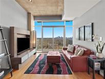 Bright living room featuring a red leather sofa, modern rug, and expansive windows with skyline views at 250 Pharr Ne Rd # 1812, Atlanta, GA 30305