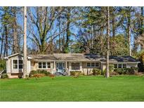 Charming brick ranch-style home boasts a lush lawn and mature trees at 1716 N Springs Dr, Atlanta, GA 30338