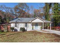 Charming white home featuring a covered carport, light blue door, and well-maintained lawn at 1649 Derry Sw Ave, Atlanta, GA 30310