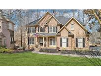 Beautiful two-story home featuring a manicured lawn, stone accents, and covered front porch with the American flag at 2883 Misty Rock Cv, Dacula, GA 30019