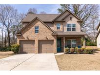 Two-story brick home features a two-car garage, a covered front porch, and lush landscaping at 3894 Dunaire Dr, Stone Mountain, GA 30083