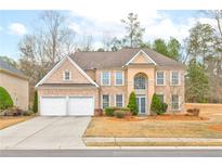 Two-story brick home with a two-car garage and well-manicured front lawn at 3143 Wolf Club Dr, Atlanta, GA 30349