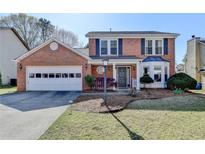 Charming two-story brick home featuring a well-maintained front yard, attached garage, and inviting entrance at 2940 Abbotts Pointe Dr, Duluth, GA 30097