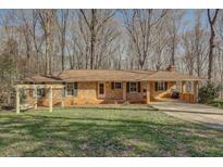 Charming ranch-style home featuring a brick facade, covered carport, and inviting front yard space at 2870 Carla Nw Dr, Kennesaw, GA 30144