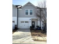Charming townhome featuring a one-car garage, modern facade, and well-manicured landscaping at 5432 Plain Field Ln, Lilburn, GA 30047
