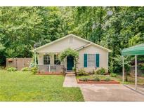 Charming single-story home with lush landscaping, a covered front porch, and vibrant blue shutters at 6675 Overton Cir, Cumming, GA 30041