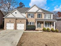 Traditional brick home featuring a two-car garage, landscaped front yard, covered porch and classic architectural details at 2536 Kachina Trl, Dacula, GA 30019