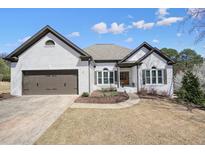 Charming one-story brick home featuring a two-car garage and well-manicured lawn at 1090 Compton Way, Suwanee, GA 30024