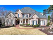 Beautiful brick home with a manicured lawn, brick walkway, and covered front porch at 6950 Kettering Ln, Suwanee, GA 30024