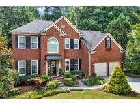Charming two-story brick home featuring a well-manicured lawn, mature trees, and a two car garage at 2138 Jockey Hollow Nw Dr, Kennesaw, GA 30152