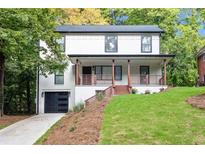 Charming two-story home with a covered front porch, black garage door, and beautifully landscaped yard at 276 Hermer Nw Cir, Atlanta, GA 30311